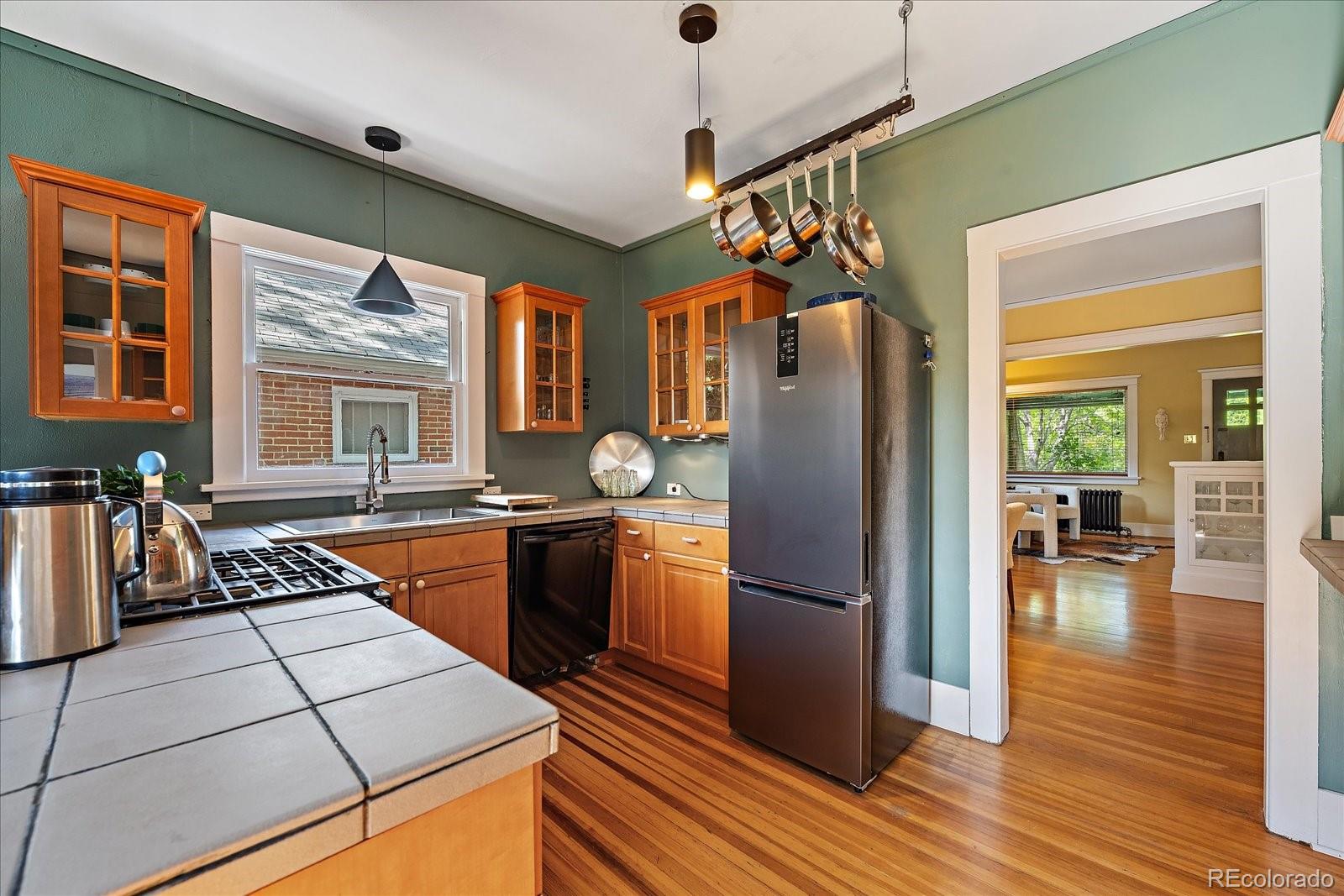 756 Steele Street Denver, CO 80206 - Photo 13 of 32 a kitchen with stainless steel appliances granite countertop a refrigerator stove and wooden floor