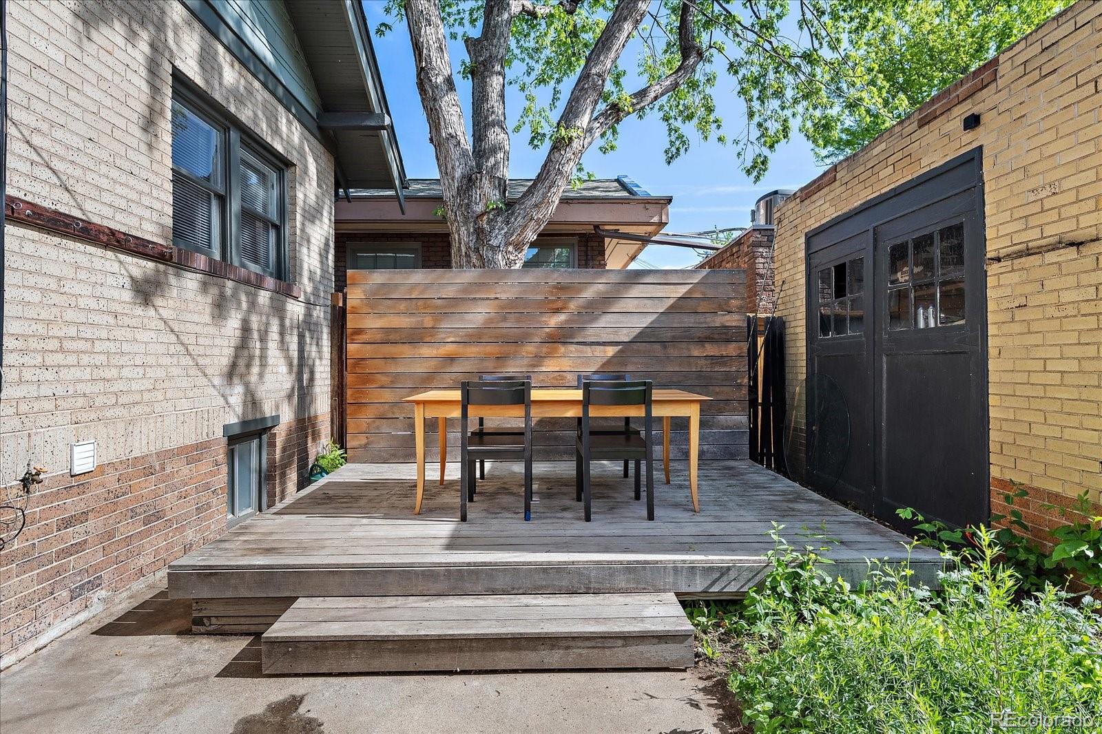 756 Steele Street Denver, CO 80206 - Photo 20 of 32 a view of a patio with table and chairs with wooden floor and fence