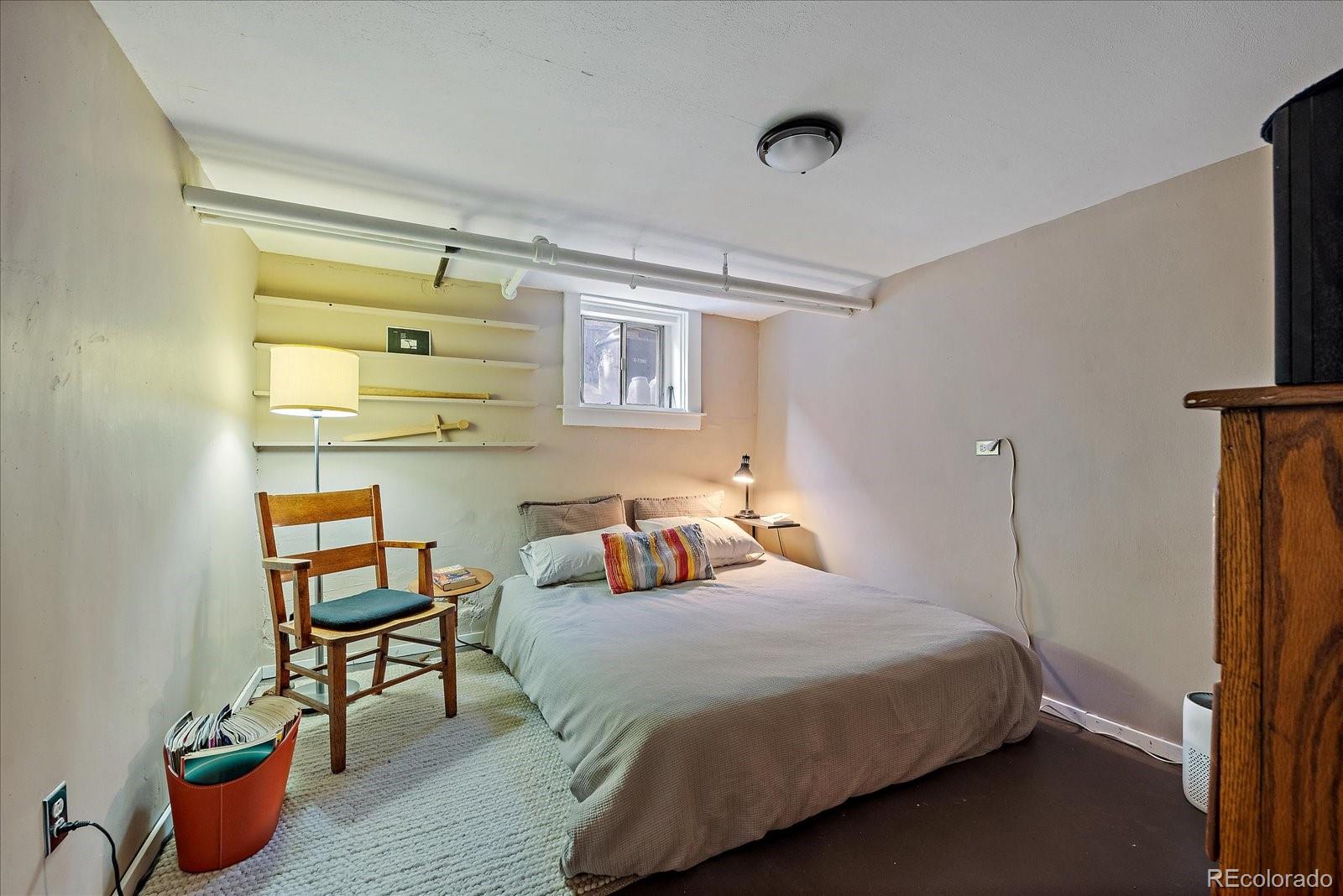 756 Steele Street Denver, CO 80206 - Photo 23 of 32 a bedroom with a bed a table and painting on the wall