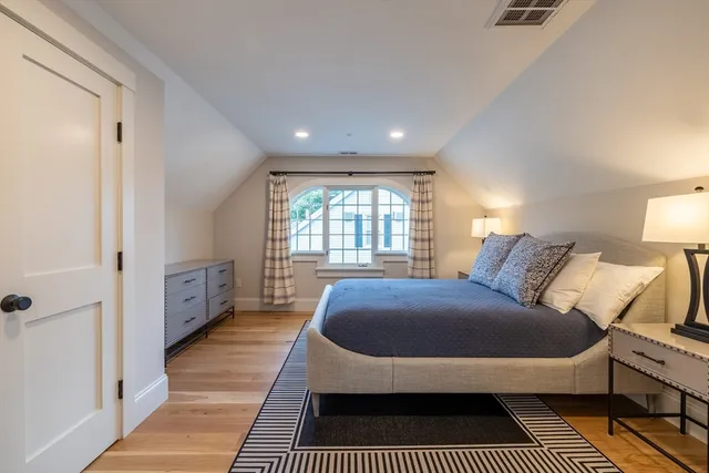 a spacious bedroom with a bed a dresser and a large window