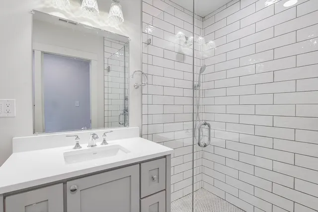 a bathroom with a sink shower and a mirror