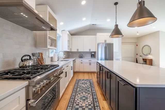 a kitchen with kitchen island stainless steel appliances a stove a sink a center island and windows