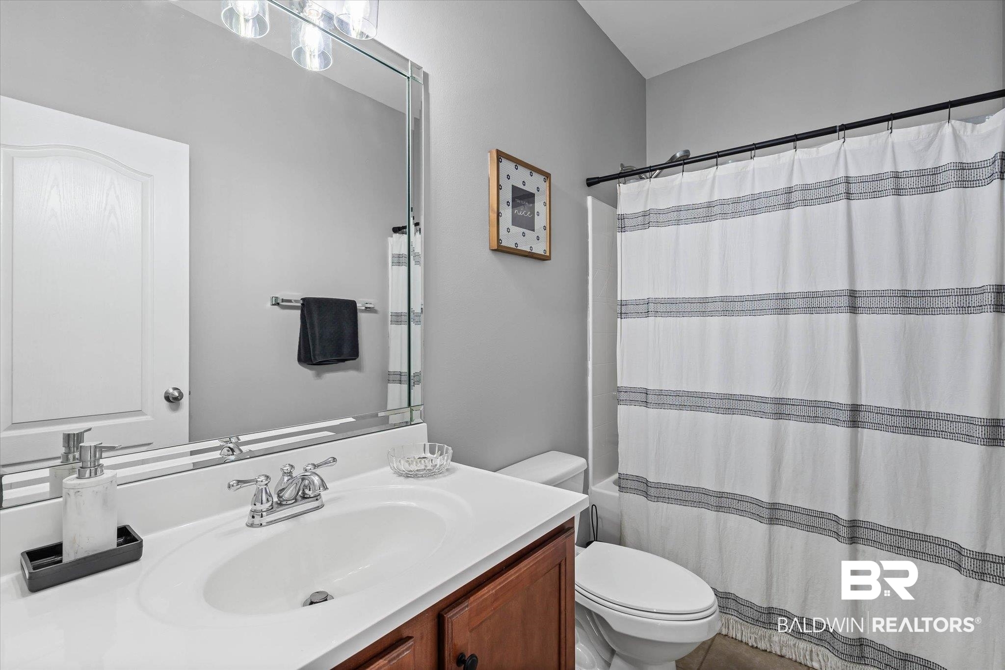 3739 Whitestone Drive Semmes, AL 36575 - Photo 17 of 25 Bathroom featuring a vanity with a white countertop and an integrated sink, polished chrome faucet, wood-finish cabinetry, and a framed mirror with overhead lighting