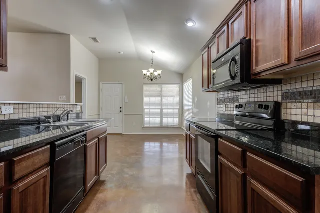a kitchen with stainless steel appliances granite countertop a stove a sink and a microwave