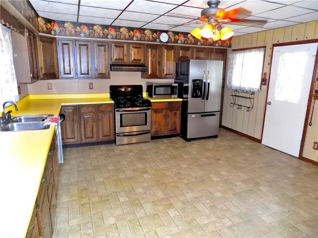 a kitchen with stainless steel appliances kitchen island granite countertop a refrigerator and a stove top oven