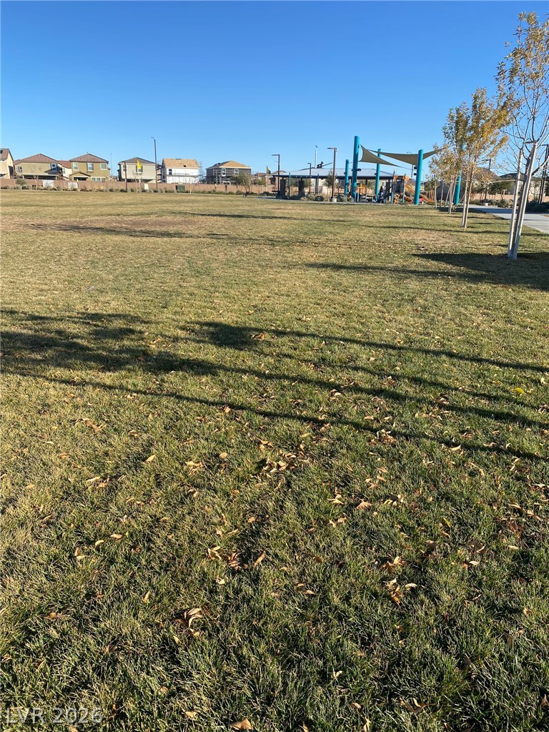 916 Riggs Flats Avenue North Las Vegas, NV 89086 - Photo 4 of 43 An expansive green lawn sits adjacent to a community playground under a clear blue sky.