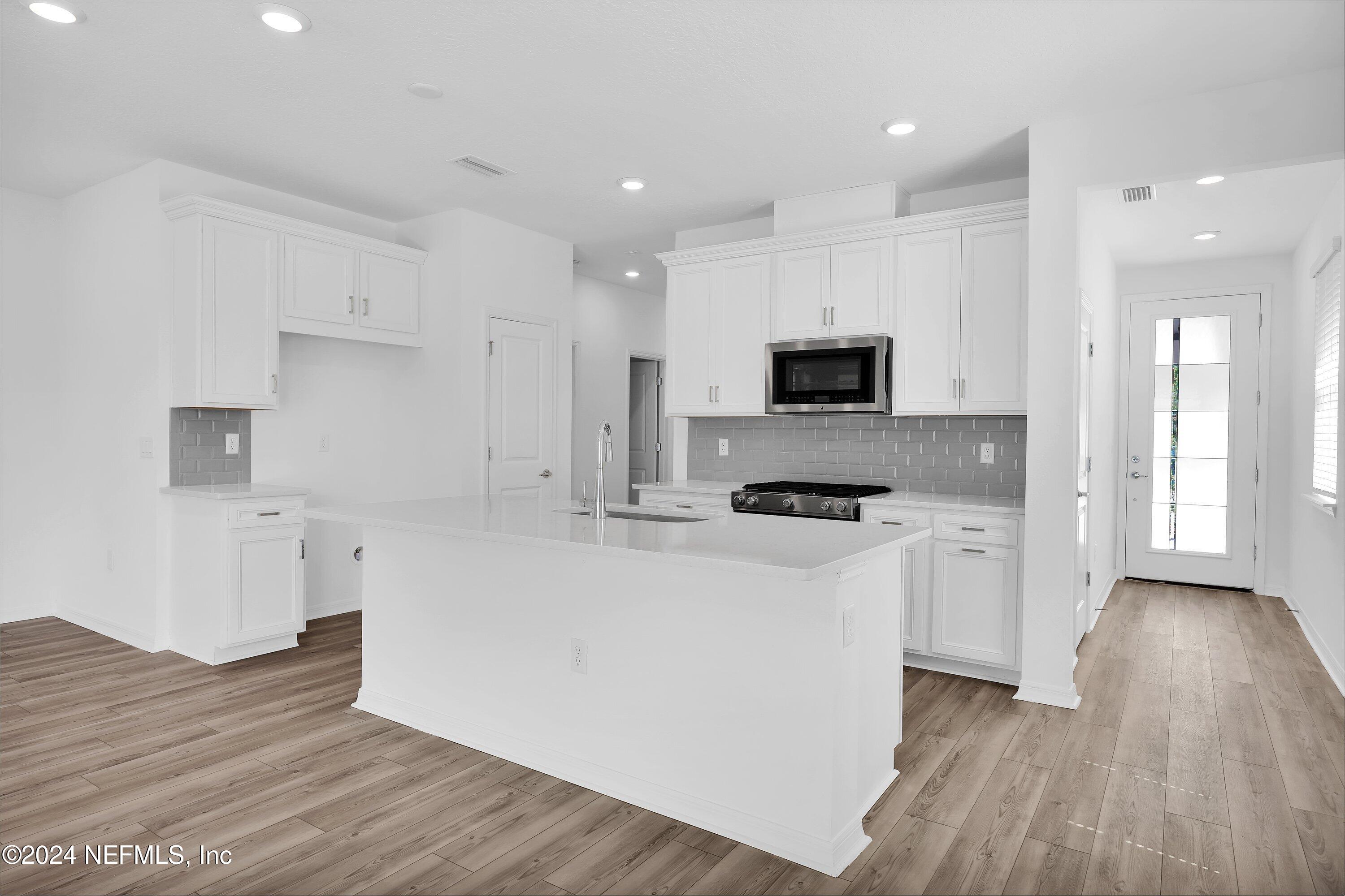 152 Flintlock Lane St. Augustine, FL 32095 - Photo 3 of 40 a large kitchen with stainless steel appliances granite countertop a stove a sink and a microwave