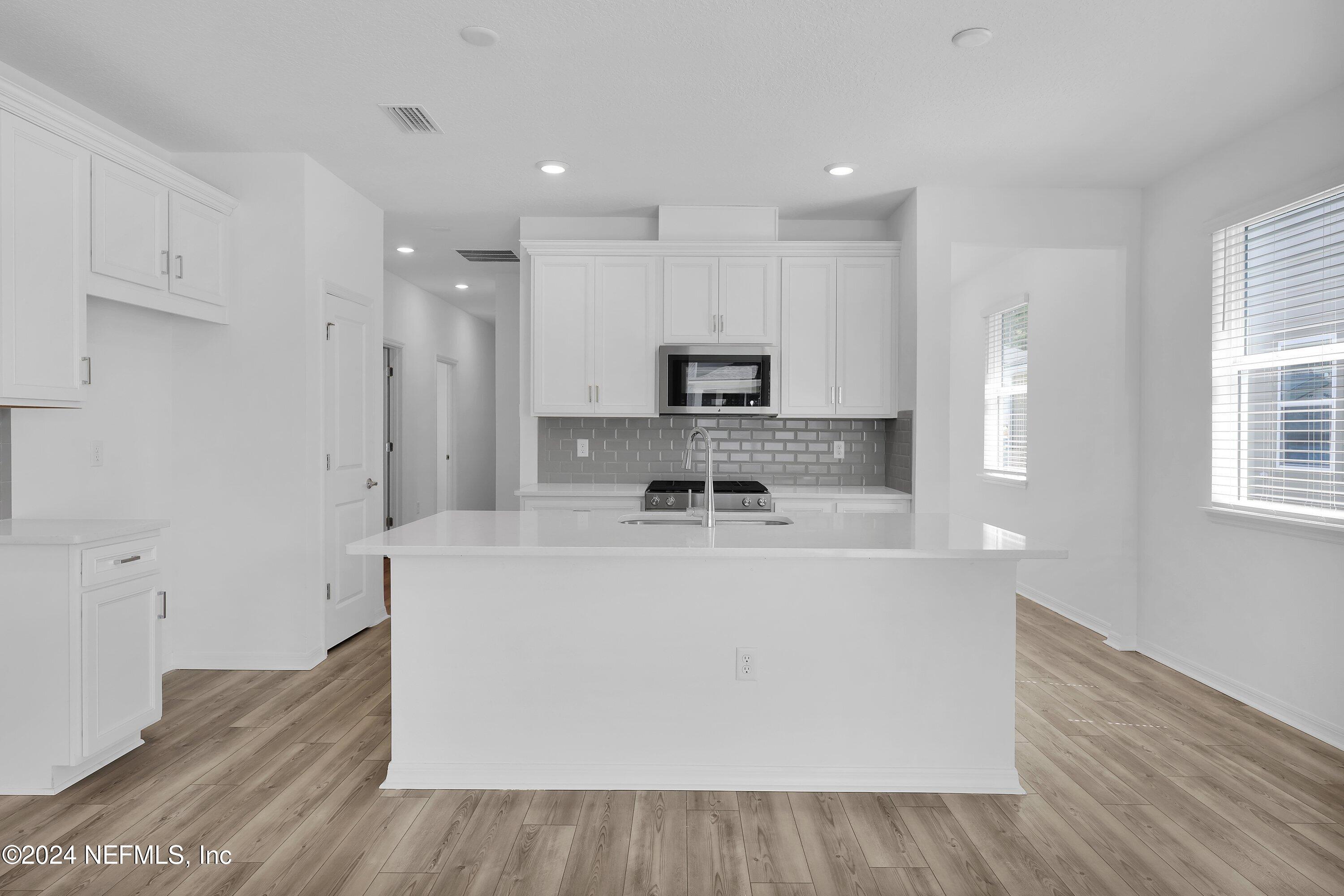 152 Flintlock Lane St. Augustine, FL 32095 - Photo 5 of 40 a large kitchen with stainless steel appliances granite countertop a stove a sink a refrigerator and white cabinets with wooden floor