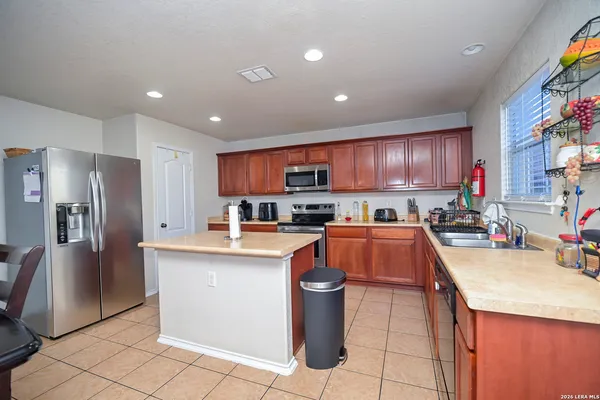 a kitchen with stainless steel appliances granite countertop a refrigerator a sink a stove a microwave and a refrigerator