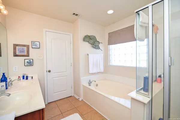 a bathroom with a tub a sink and a large mirror