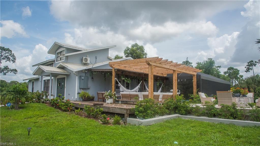 3220 63rd Street Southwest Naples, FL 34105 - Photo 2 of 36 Rear view of house featuring a pergola, a yard, stucco siding, and a deck