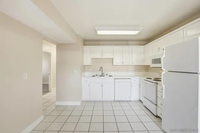 a kitchen with white cabinets a sink and white appliances