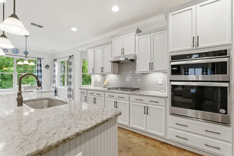 a kitchen with granite countertop a stove a sink and a refrigerator