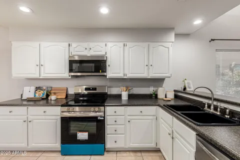 a kitchen with granite countertop white cabinets and a stove top oven