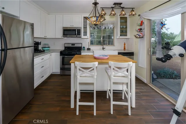 a kitchen with a refrigerator a stove a microwave and dining table with wooden floor