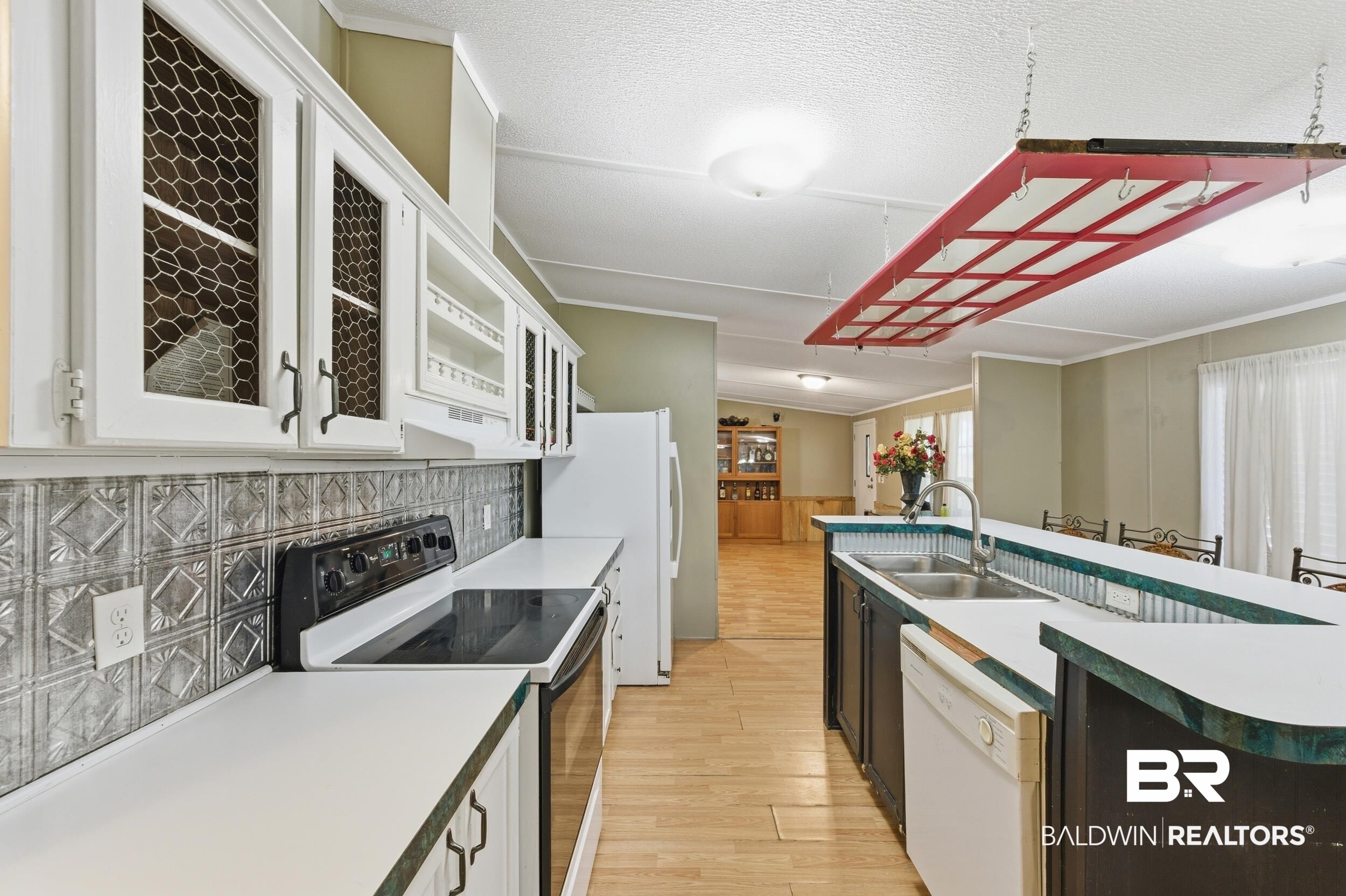 926 Tumbling Lane Atmore, AL 36502 - Photo 19 of 56 Kitchen featuring white cabinetry with chicken wire inserts, a patterned metal backsplash, and light wood-finish flooring
