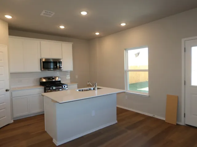 a room with wooden floor and white cabinets