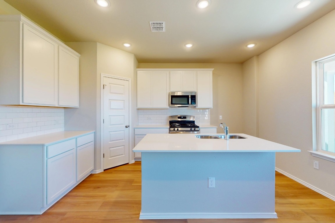 12300 Dillon Fls Drive Austin, TX 78747 - Photo 8 of 40 a room with kitchen island a sink a stove and a refrigerator