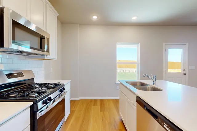 a kitchen with stainless steel appliances a stove a sink and a microwave