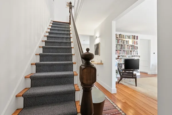 a view of a hallway with wooden floor and a bathroom
