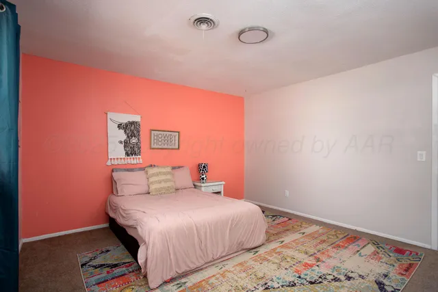 a bedroom with a bed and a lamp on the dresser