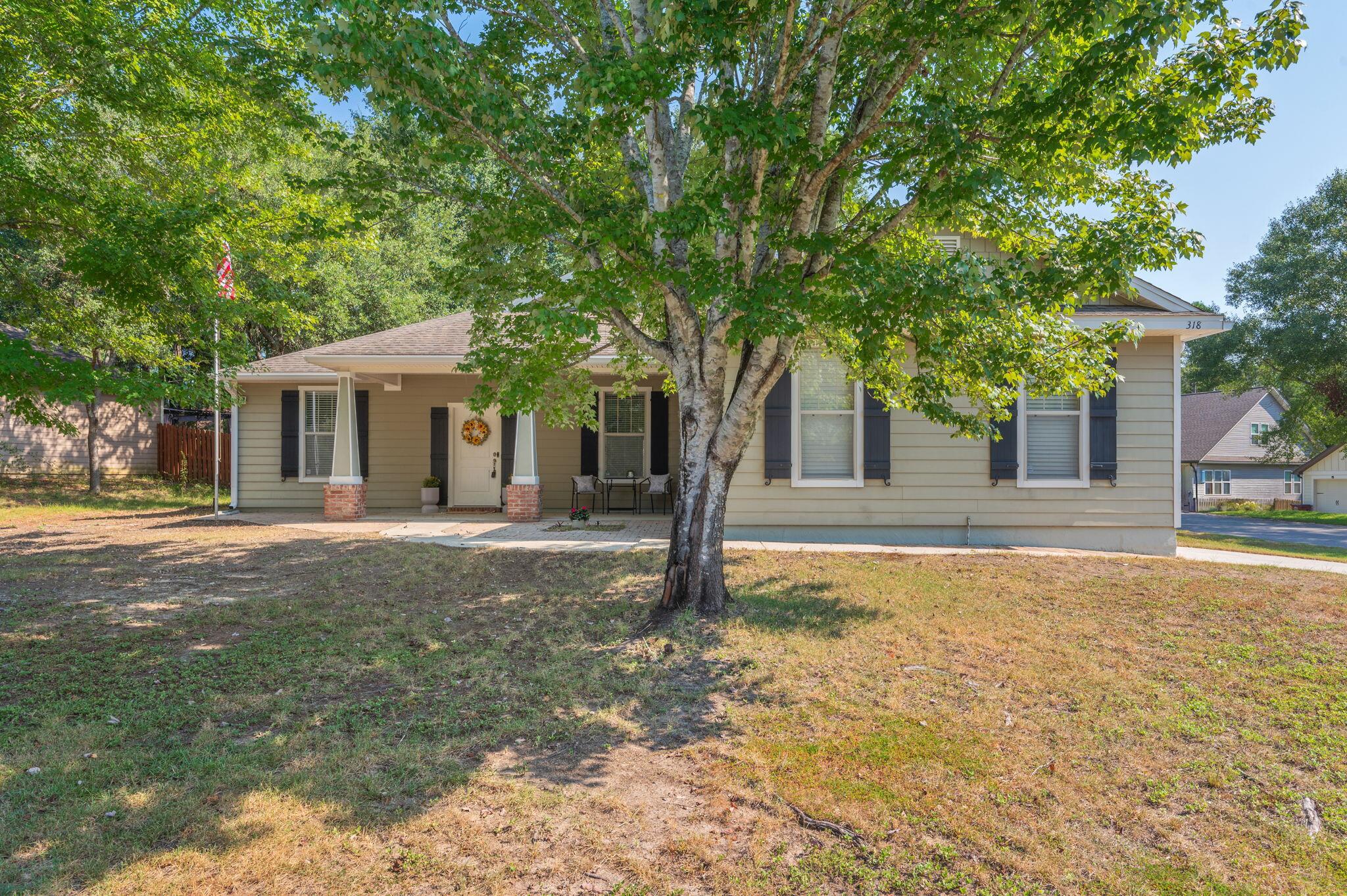 a front view of a house with yard tree and tree