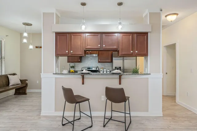 a kitchen with a refrigerator a stove a sink and a dining table with wooden floor