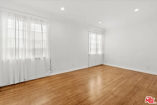 an empty room with wooden floor fireplace and windows