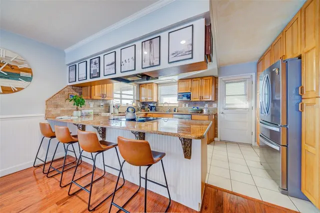 a kitchen with stainless steel appliances kitchen island granite countertop wooden cabinets a dining table and chairs
