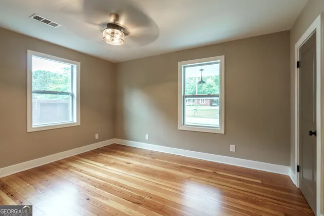 a view of empty room with wooden floor and fan