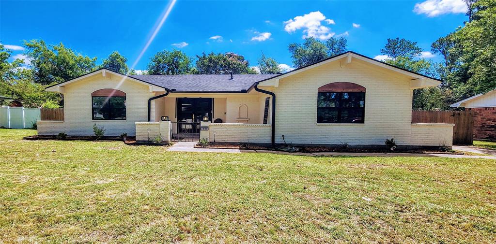 2908 Washington Street Commerce, TX 75428 - Photo 4 of 29 Cream-colored brick exterior featuring a black shingle roof, arched window details, and dark-framed windows