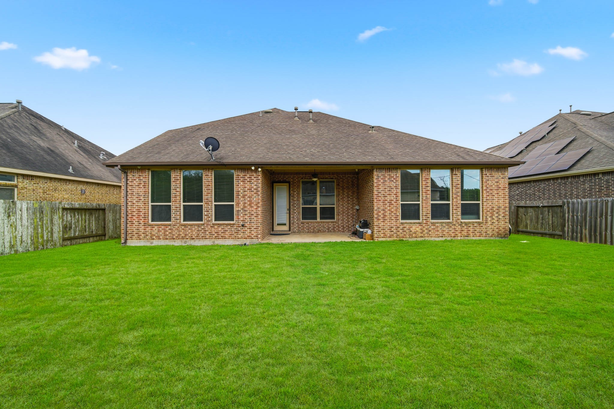 5303 Mesquite Willow Lane Rosharon, TX 77583 - Photo 31 of 32 The house features multiple large windows and a covered patio area, perfect for outdoor relaxation.