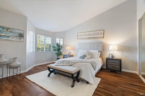 a bedroom with a bed a table and windows