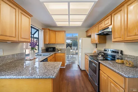 a kitchen with granite countertop a sink a counter space appliances and cabinets