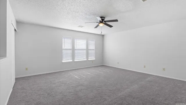 an empty room with windows and fan
