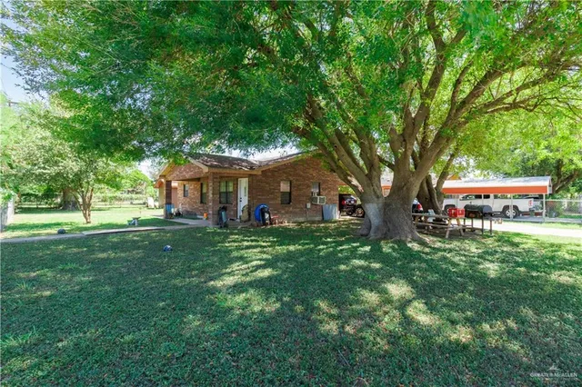 a view of a house with a big yard and large trees