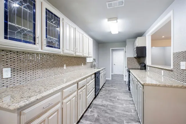 a kitchen with granite countertop a sink stove and cabinets