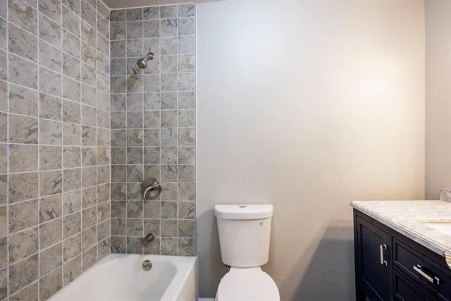 a bathroom with a granite countertop toilet a sink and bathtub