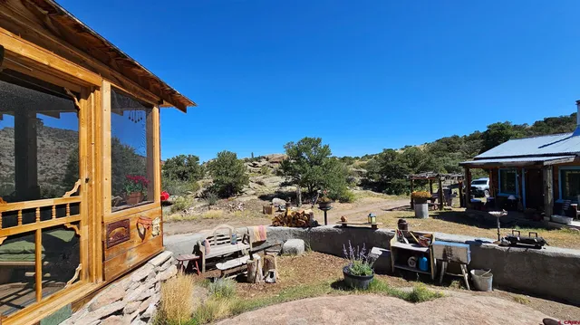 a view of a patio with couches table and chairs under an umbrella with wooden floor