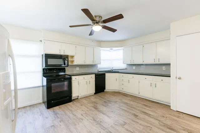 a kitchen with granite countertop white cabinets and black appliances