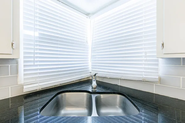 an empty room with wooden floor ceiling fan and refrigerator