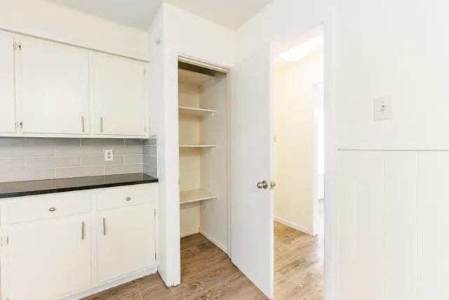 an empty room with a chandelier fan and a window