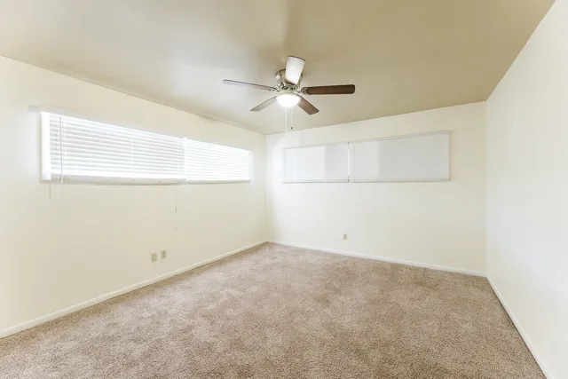 an empty room with a window and a ceiling fan