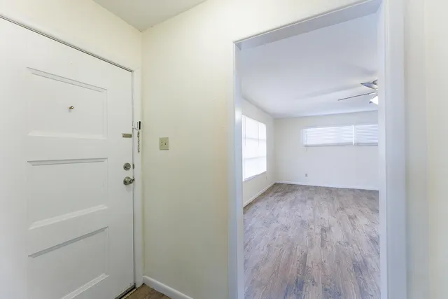 an empty room with wooden floor and chandelier fan