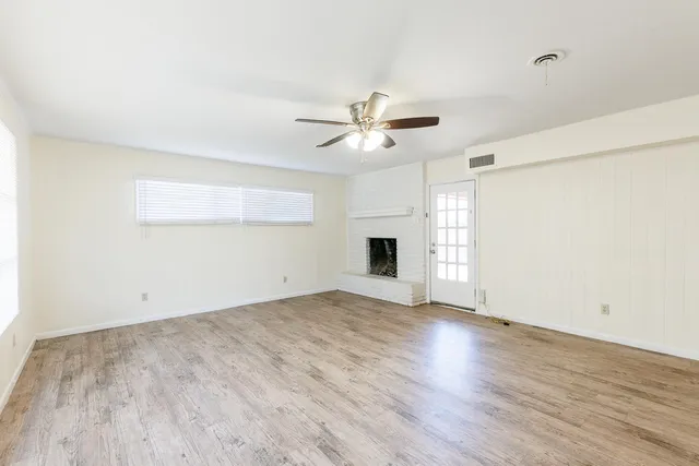 an empty room with windows and fireplace