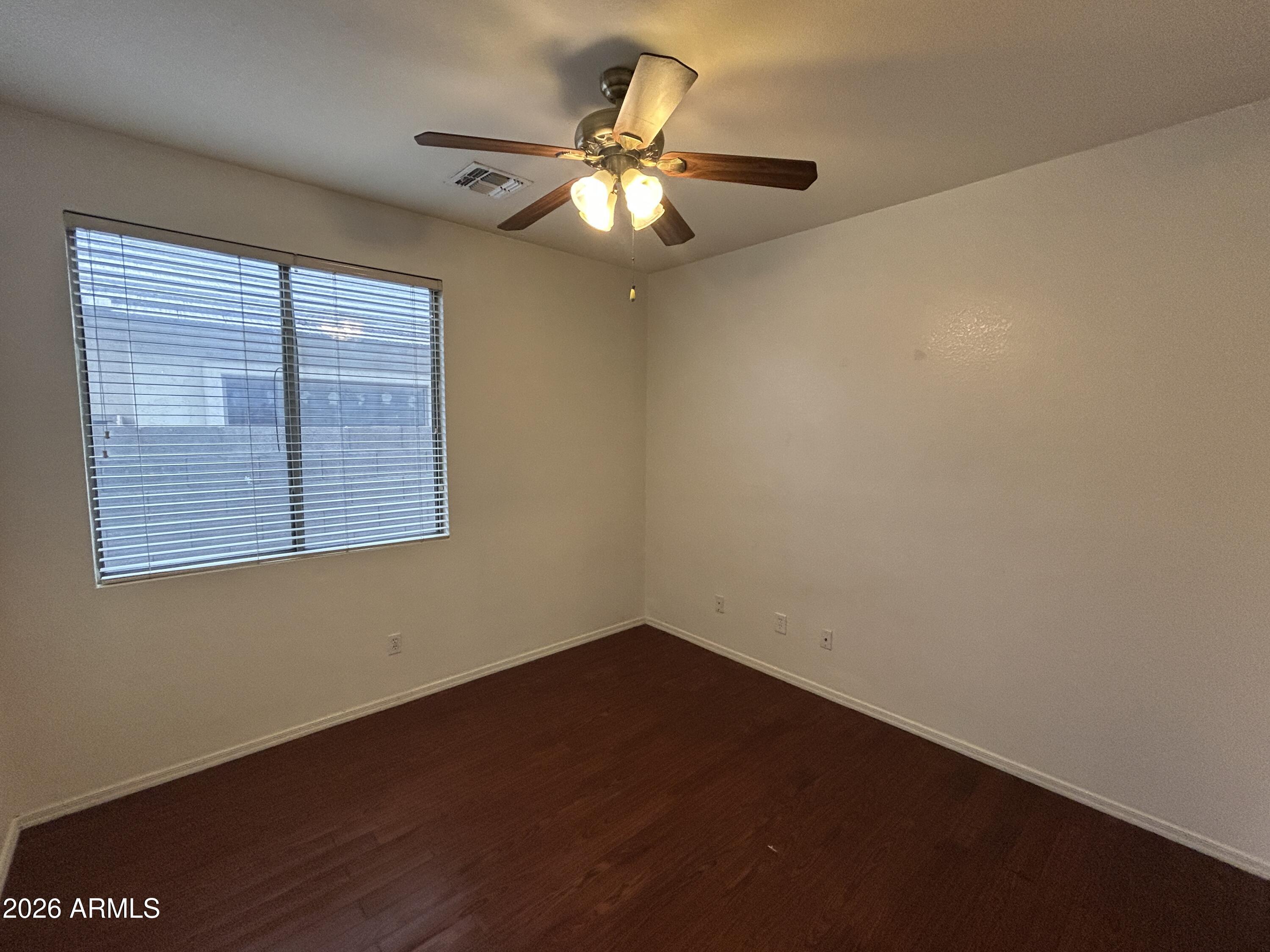 2202 West Carter Road Phoenix, AZ 85041 - Photo 12 of 20 a view of an empty room with wooden floor and a window