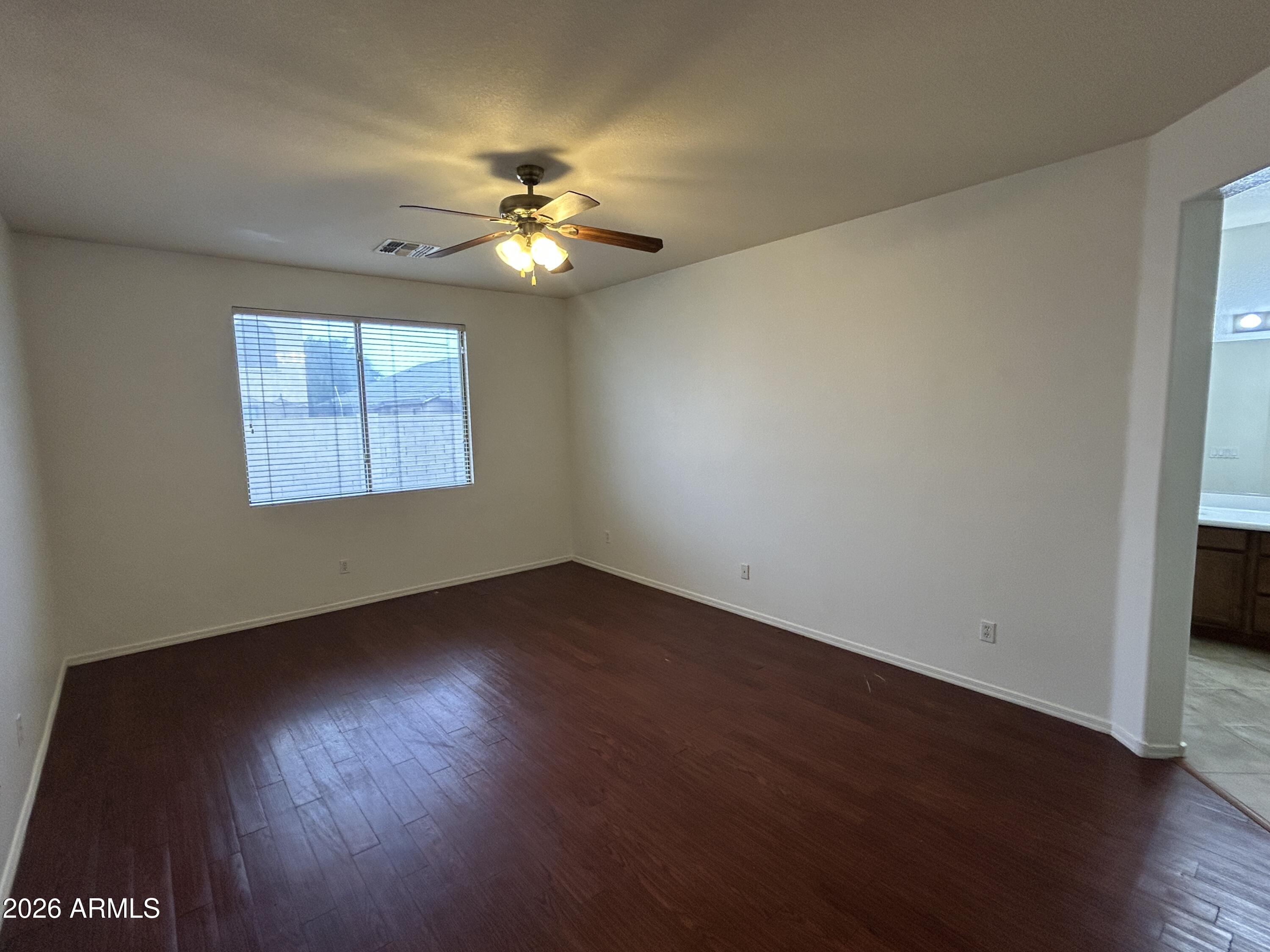 2202 West Carter Road Phoenix, AZ 85041 - Photo 14 of 20 a view of an empty room with wooden floor and a window
