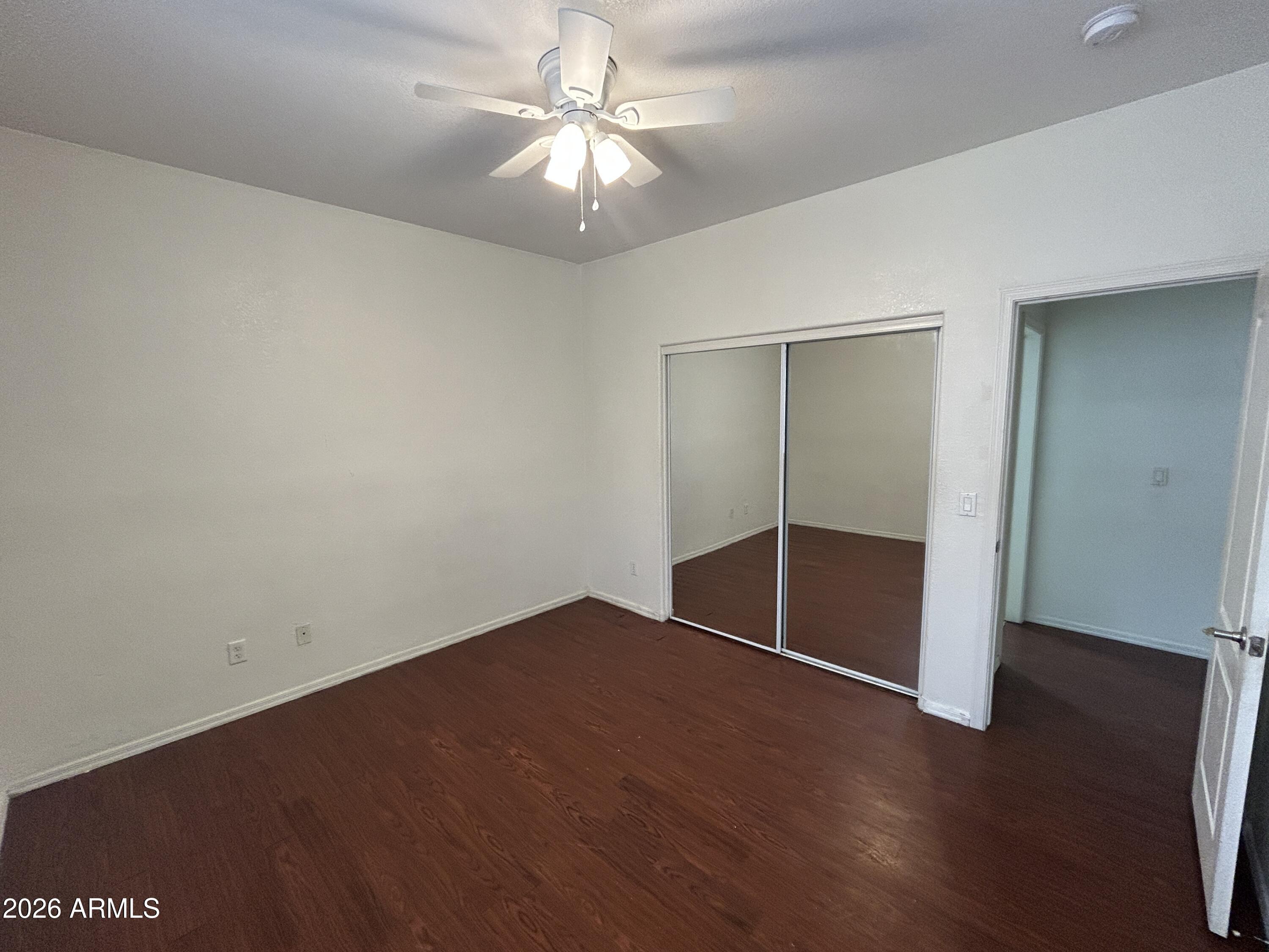 2202 West Carter Road Phoenix, AZ 85041 - Photo 9 of 20 an empty room with wooden floor fan and windows