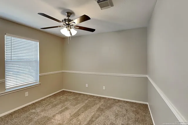 an empty room with a window and a fan