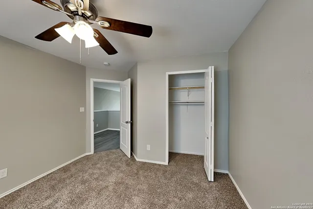 an empty room with closet and a ceiling fan